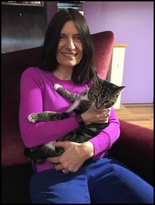 Alexandra with cat in arms seated at desk